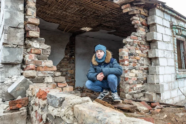 Un niño en una casa en ruinas, un adolescente quedó sin hogar como resultado de conflictos militares y desastres naturales . —  Fotos de Stock