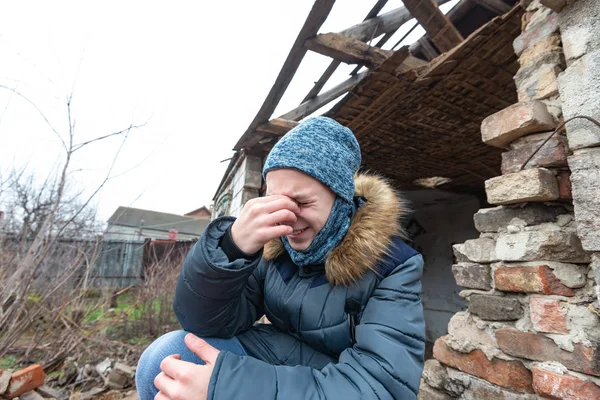 Подросток сидит на камнях разрушенного дома и плачет о потере своих близких в результате военных конфликтов . — стоковое фото
