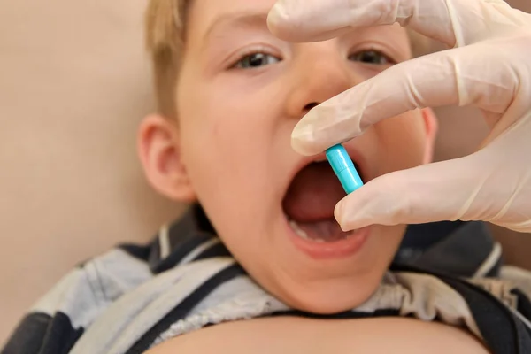Az orvos tablettákat ad egy beteg gyermeknek, hogy kezelje a betegséget és felépüljön.. — Stock Fotó