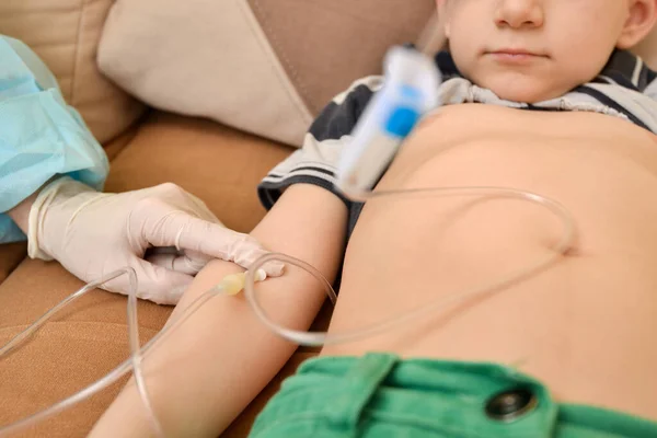 Doktor hasta bir çocuğa evde damar içi damlatıcı enjekte ediyor..