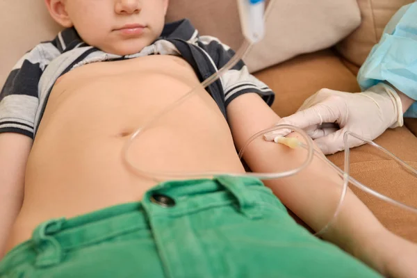 Il medico somministra un'iniezione a un bambino malato con un contagocce endovenoso a casa . — Foto Stock