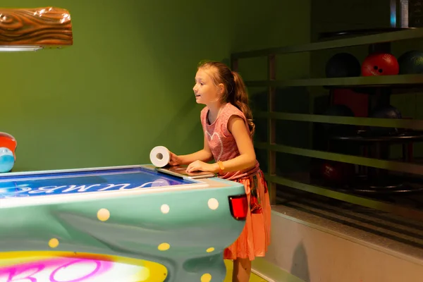 Joyful girl plays air hockey in a children\'s game complex.