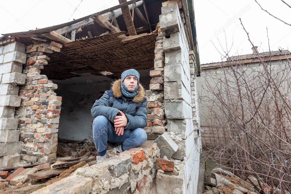 A boy in a ruined house, a teenager was left homeless as a result of military conflicts and natural disasters.