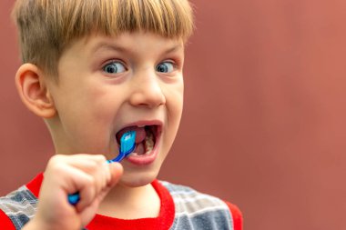 Çocuk ağzının yanında elinde bir diş fırçası tutuyor..