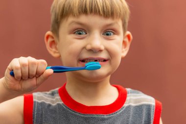 Çocuk ağzının yanında elinde bir diş fırçası tutuyor..