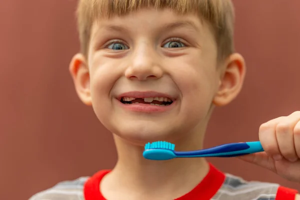 The child holds a toothbrush in his hand near his mouth. — Stock Photo, Image