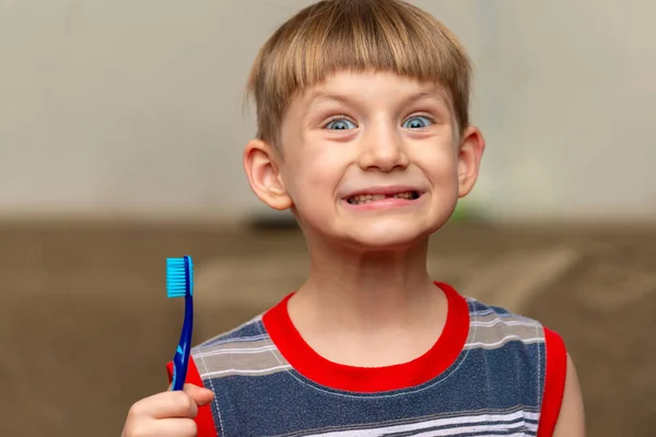 Chłopiec trzyma w ręku szczoteczkę do zębów z czystymi zębami.. — Zdjęcie stockowe