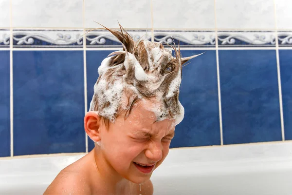 A boy with a soapy head from shampoo in the bath while bathing. — Stock Photo, Image
