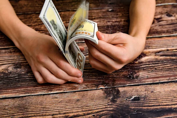 Человек, листающий над связкой долларов на темном деревянном фоне, концепция финансовой независимости . — стоковое фото