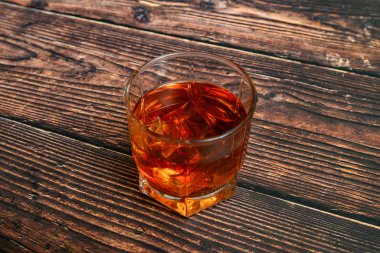 Ahşap bir arka planda, cam kadehte alkol, konyak, viski, buzlu konyak..