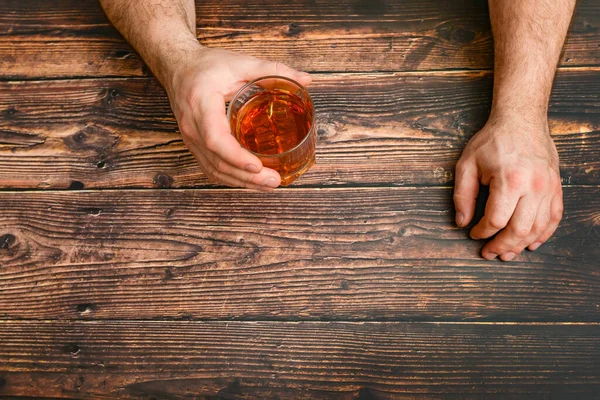 Un hombre levanta un vaso de alcohol con la esperanza de una bebida para la intoxicación. El concepto de alcoholismo y dependencia del alcohol . — Foto de Stock
