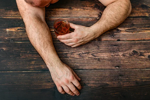 O homem bêbado com um copo de álcool está em uma mesa de madeira. O conceito de alcoolismo e dependência de álcool . — Fotografia de Stock