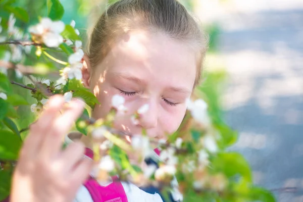 Una chica huele flores en un árbol con los ojos cerrados . —  Fotos de Stock