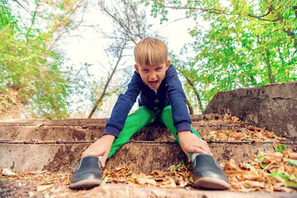 Egy fiú ül a lépcsőn a parkban, széles látószögű fénykép. — Stock Fotó