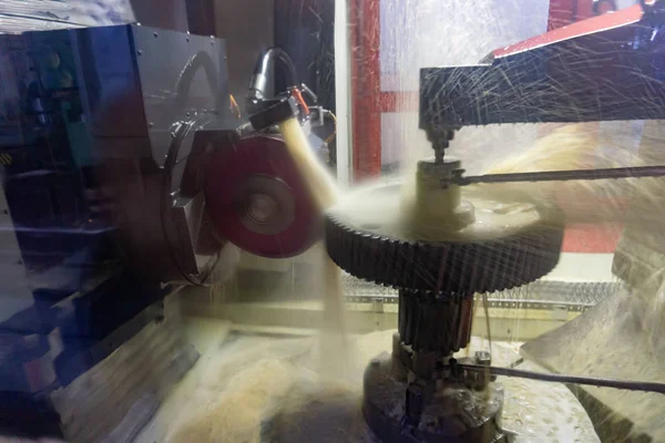 Schleifstein erzeugt ein hochpräzises Zahnradschleifen auf einer CNC-Maschine, Öl als Kühlmittel. — Stockfoto