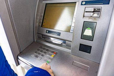 A woman at an ATM presses a button to withdraw cash.