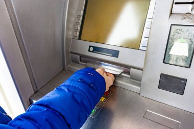 A woman at an ATM withdraws cash hryvnias in Ukraine, 100 and 500 hryvnia notes.