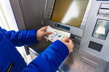 A woman at an ATM withdraws cash hryvnias in Ukraine, 100 and 500 hryvnia notes.