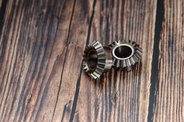 Two bevel gears after manufacturing lie on a wooden background.