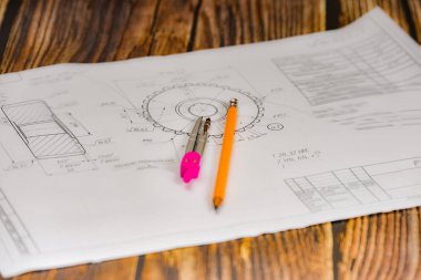 Pencil, compass and technical drawing on a dark wooden background.