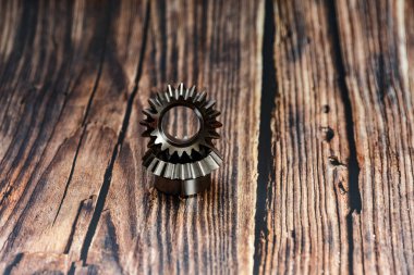 Two bevel gears after manufacturing lie on a wooden background.