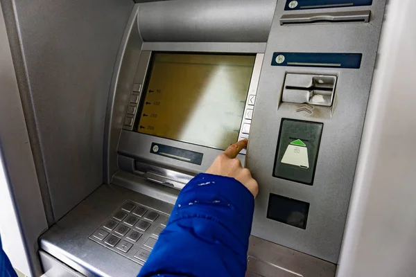 En kvinne i en minibank trykker på en knapp for å ta ut penger. . – stockfoto