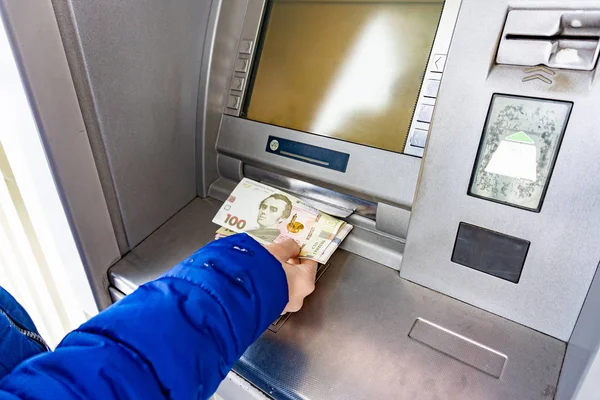 A woman at an ATM withdraws cash hryvnias in Ukraine, 100 and 500 hryvnia notes. — Stok fotoğraf