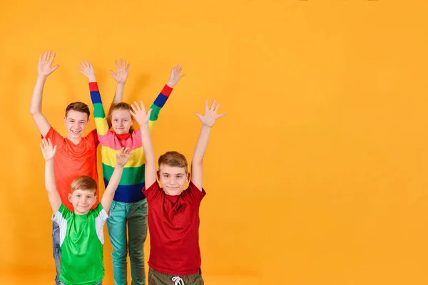 Quatre enfants en vêtements colorés se lèvent la main, un endroit pour le texte publicitaire . — Photo