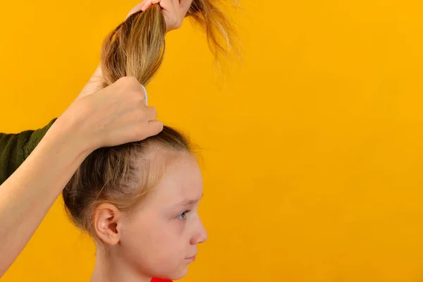 Mom does her daughter's hair by braiding her hair in braids and a tail. — Stock Photo, Image