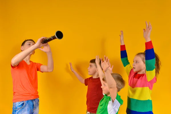 Choeur d'enfants accompagné de clarinette. Le garçon joue de la clarinette aux enfants, et ils chantent et lèvent les mains . — Photo