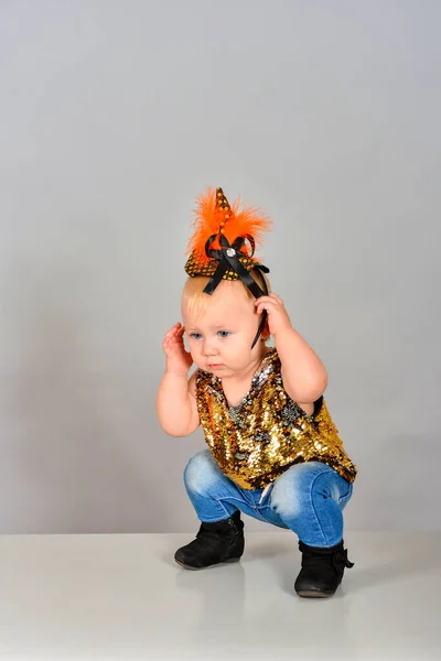 Year-old girl dressed in the style of 80-90 years. A small child in jeans and sequins poses in a modeling agency. — Stock Photo, Image
