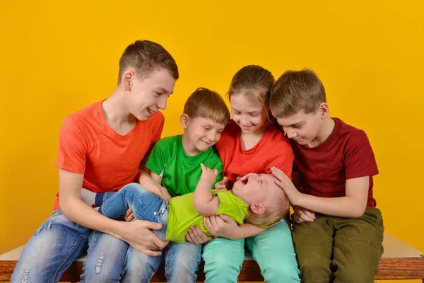 Чотири дитини тримають маленьку дитину на руках, щасливих і радісних братів і сестер . — стокове фото