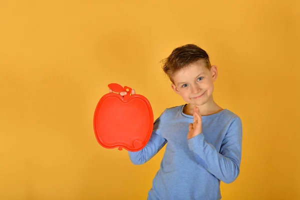 男孩手里拿着一个苹果形状的空白红盘 一个做广告或登记的地方 — 图库照片