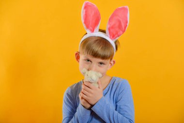 Tavşan kulaklı bir çocuk elinde oyuncak bir tavşan tutuyor, çocuklar Paskalya partisi için hazırlanıyor..
