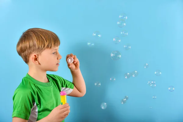 Мальчик Зелёной Футболке Надувает Пузырьки Воздуха Синем Фоне — стоковое фото