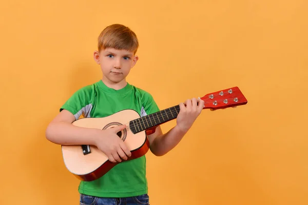 Chłopiec Trzyma Gitarę Dłoniach Żółtym Tle — Zdjęcie stockowe
