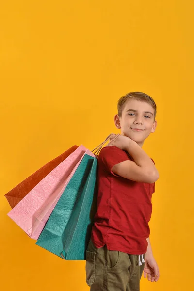 彼の手に色の袋が付いている喜び 幸せなバイヤーは購入からの彼の肯定的な感情を示す 黄色の背景で購入した赤ちゃん — ストック写真