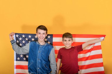 İki genç kardeş Amerikan bayrağının önünde duruyor. Genç izciler vatansever..