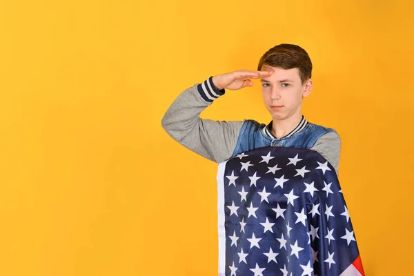 Nastolatek Salutuje Trzymając Rękę Czole Trzyma Amerykańską Flagę Klatce Piersiowej — Zdjęcie stockowe