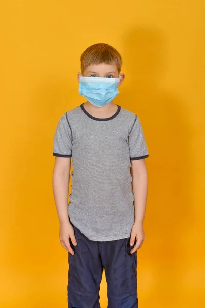 一个男孩站在一个黄色背景的保护膜上 儿童和个人防护设备 — 图库照片