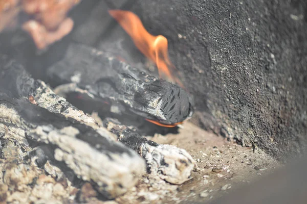 Burning log with coals and ash closeup.