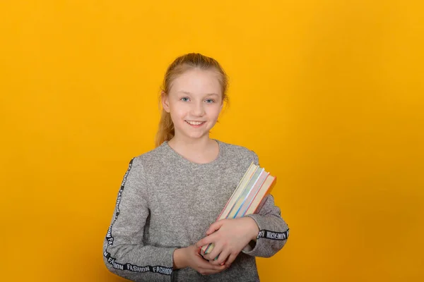 Mädchen Mit Schulbüchern Der Hand Steht Auf Gelbem Hintergrund — Stockfoto