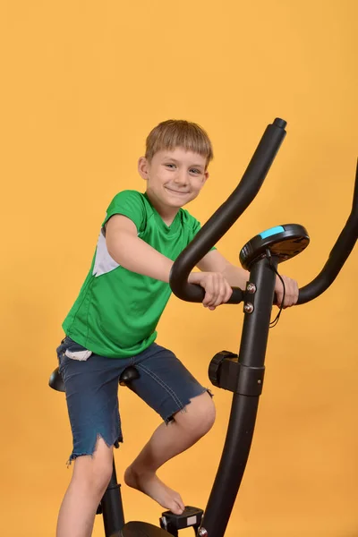 Menino Entra Para Esportes Criança Uma Bicicleta Estacionária Faz Cardio — Fotografia de Stock