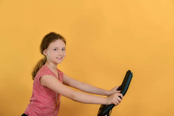 Menina Entra Para Esportes Criança Uma Bicicleta Estacionária Faz Cardio — Fotografia de Stock