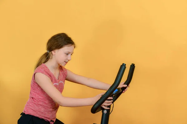 一个快乐的女孩骑着一辆跑车 在一个黄色背景的工作室里为一个青少年画像 — 图库照片