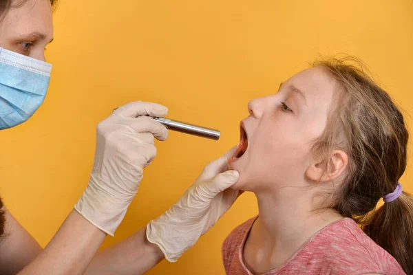 女医生用诊断用的医疗手电筒检查女孩的口腔 — 图库照片