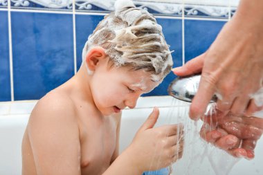 Annem elinde tuttuğu su kutusuyla bebek kafasındaki şampuanı yıkayacak..