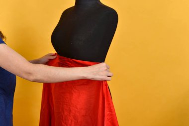 Siyah bir manken üzerinde kırmızı büyük bir bez deneyen bir kadın..