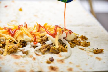 Ketçap peynir, lahana ve etin üzerine dökülür..