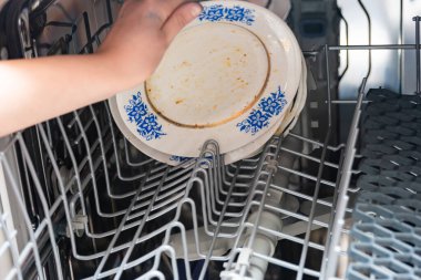 Kadın kirli tabakları bulaşık makinesine koyuyor..
